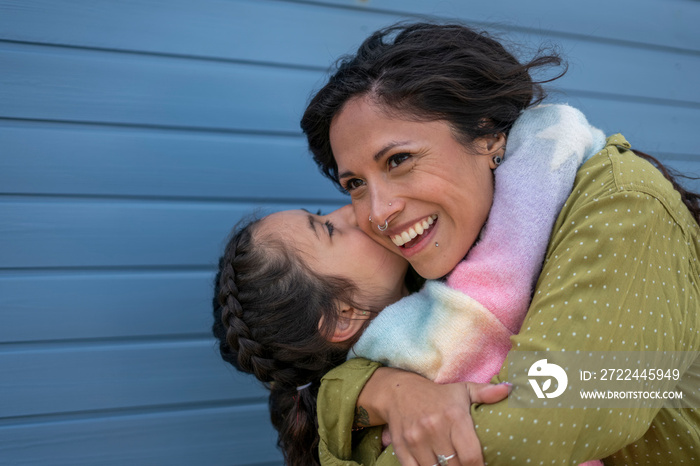 Smiling mother and daughter (8-9) hugging outdoors