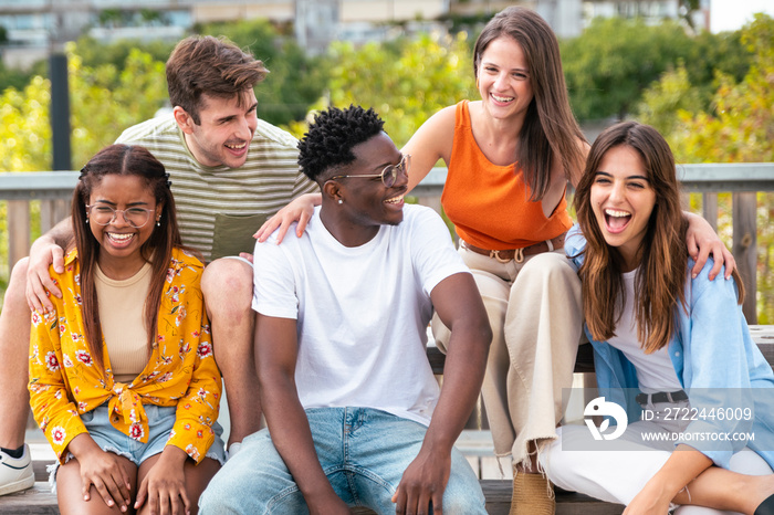 Group of five cheerful multiracial friends having fun outdoors - happy young people laughing together at city - Friendship concept.