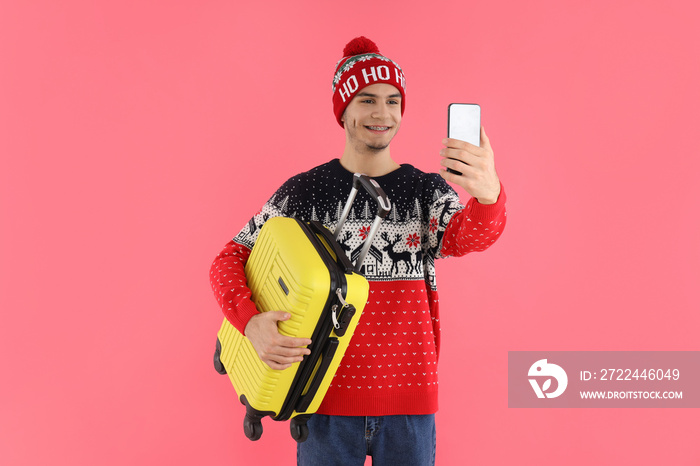 Guy in Christmas sweater with luggage bag on pink background