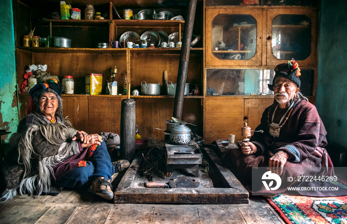 Portrait of man and woman in typical tibetan clothes inside their house in Ladakh, Kashmir, India.