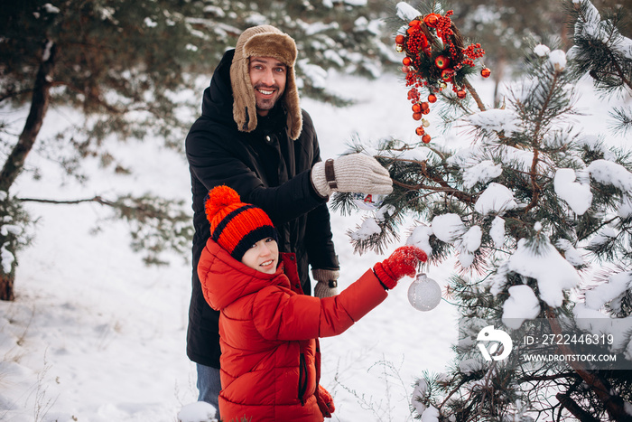 Father and son decorate the tree outdoors. Merry Christmas and Happy Holidays! Portrait loving family close up.