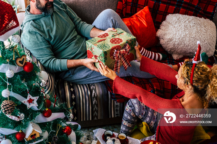 Christmas gift concept with happy woman giving present to his husband at home. Holiday new year season. Couple enjoying celebration alone with love. People and xmas time celebration relax. December