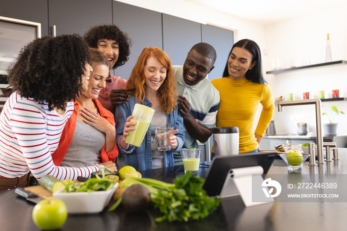 Happy diverse friends making healthy drink together in kitchen