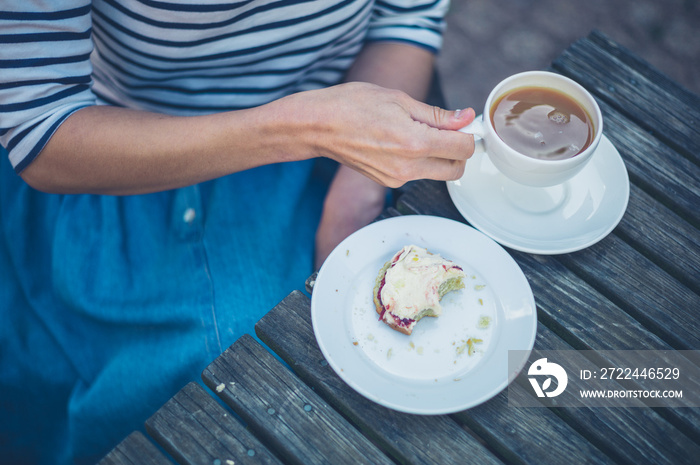 Woman drinking tea and eating scone