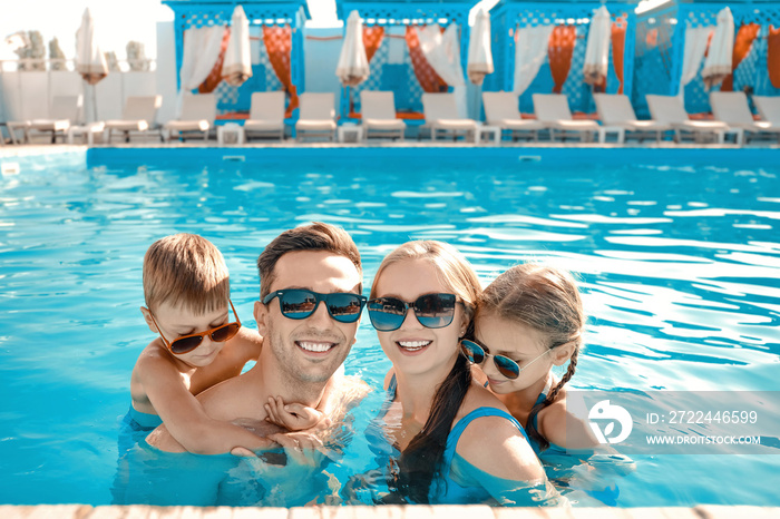 Happy family in swimming pool on summer day