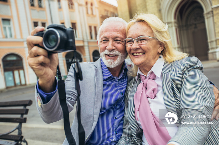 Senior couple discovering new city taking pictures on retro camera