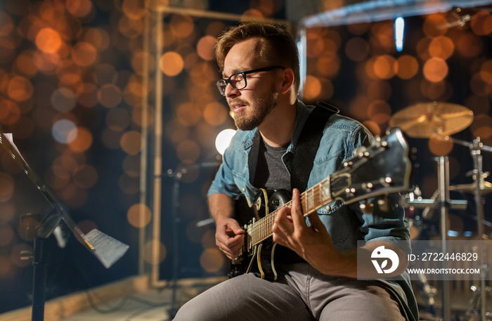 man playing guitar at studio or concert