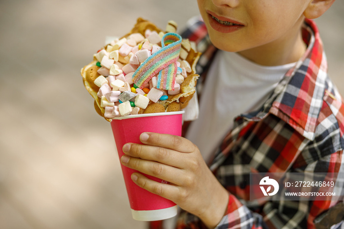 Close up of sweet waffle with marshmallows in hands of little cute boy. Kid with sweets.