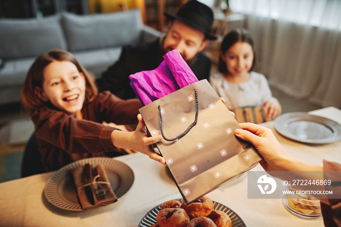 Portrait of two excited children reaching for present at jewish family celebration, copy space