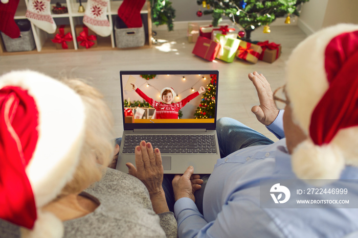 Grandparents in Santa caps video calling their happy little grandson on Christmas Day