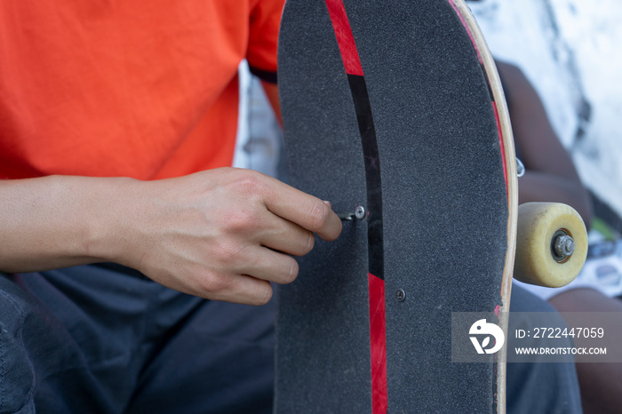 Close-up of young man fixing skateboard