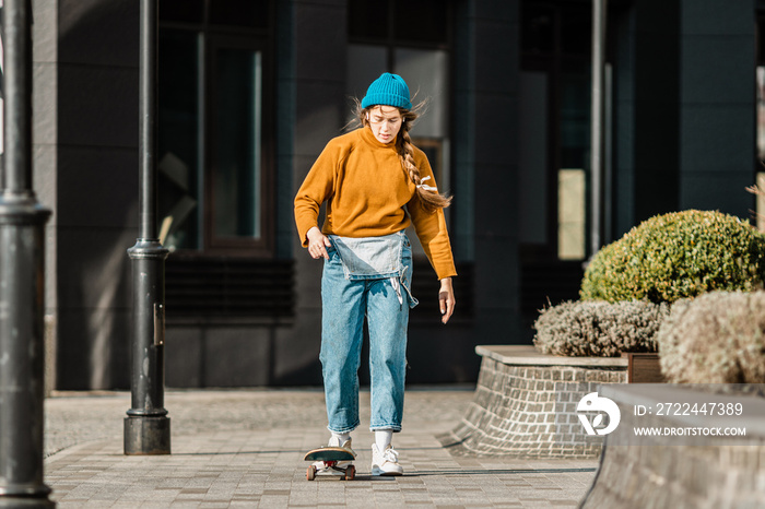 Skateboarding at city. Female, enjoyment. Hipster girl riding skate board. Ride, style. Extreme sport and emotions concept. Alternative lifestyle. Woman skateboarder skateboarding at city