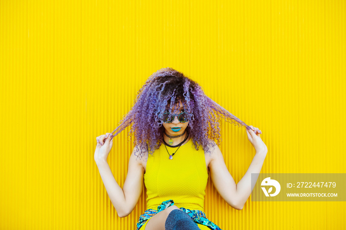 Teen millennial woman with curly hair and urban style isolated on yellow background. Bright psychedelic colors concept. Portrait of african american woman with bright colors and afro hair.