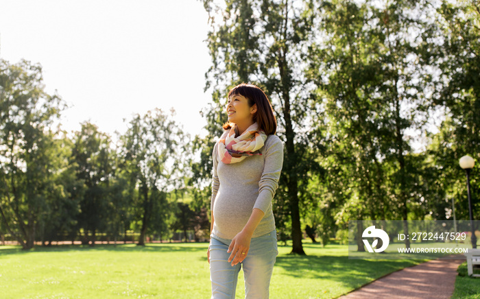 pregnancy, people and motherhood concept - happy pregnant asian woman walking at park