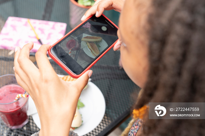 Woman photographing lunch with smart phone in garden