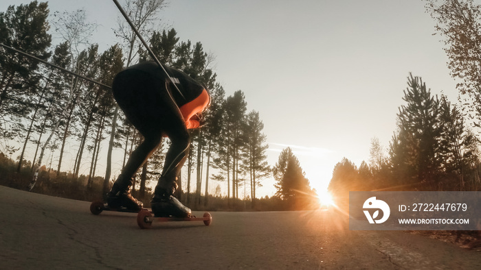 Training an athlete on the roller skaters. Biathlon ride on the roller skis with ski poles, in the helmet. Autumn workout. Roller sport. Adult man riding on skates.