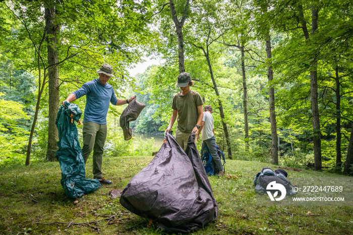 Air Force service member sets up a tent with his sons on  a backpacking trip.