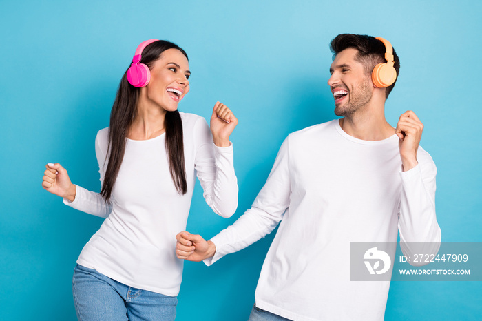 Portrait of two overjoyed positive partners listen music dancing have fun isolated on blue color background