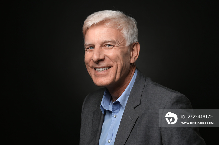 Portrait of smiling mature man on dark background