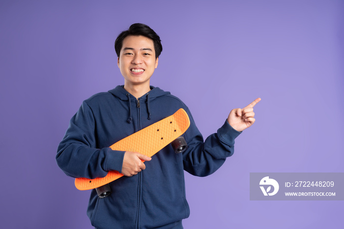 Image of young Asian man playing skateboard on purple background