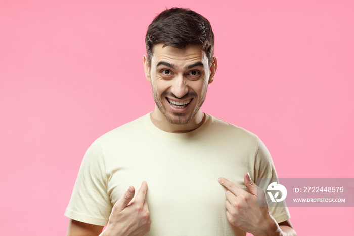 You talking to me? Young man pointing to himself with question if he did something wrong, isolated on pink background