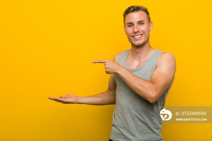 Young caucasian sport man excited holding a copy space on palm.