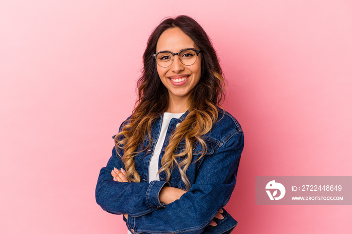 Young mexican woman isolated on pink background who feels confident, crossing arms with determination.