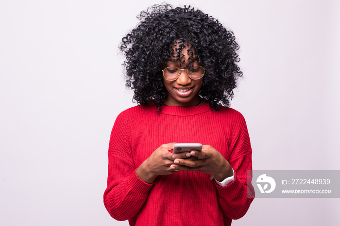 Communicating african woman with afro hairstyle using mobile phone and looking aside on copyspace isolated over white background