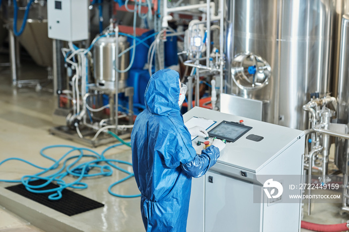 High angle view at worker in protective gear operating equipment at factory