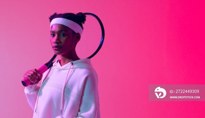 Image of african american female tennis player in neon pink lighting