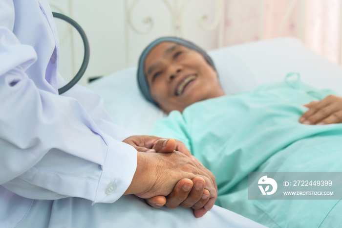 selective focused of doctor’s hands hold patient’s hands to give encouragement to patient during chemotherapy to cure cancer