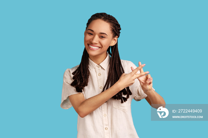 Positive popular woman blogger making hashtag sign with fingers, looking at camera with smile, tagging posts in social networks, recommending tags. Indoor studio shot isolated on blue background.