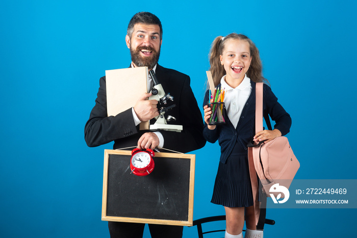 Father leading his pupil daughter to school. Portrait of modern family dad and little girls, isolated on blue background.