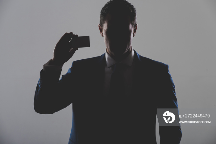 silhouette of man holding business or bank card