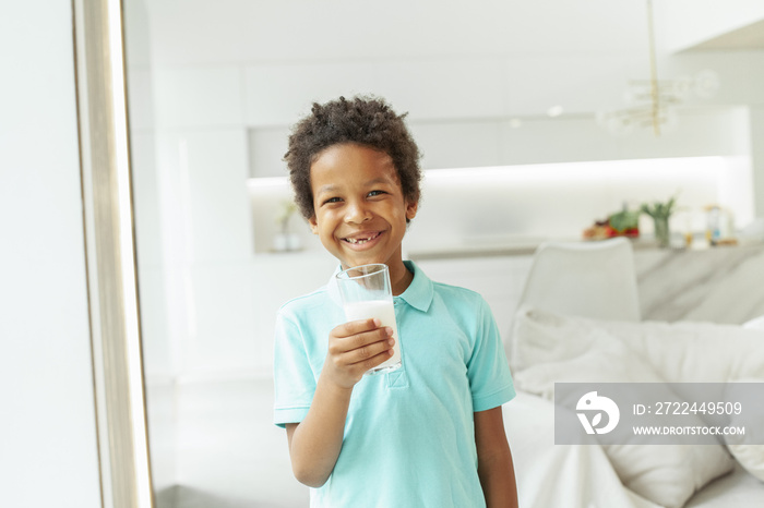 Happy smiling child boy with milk glass at home