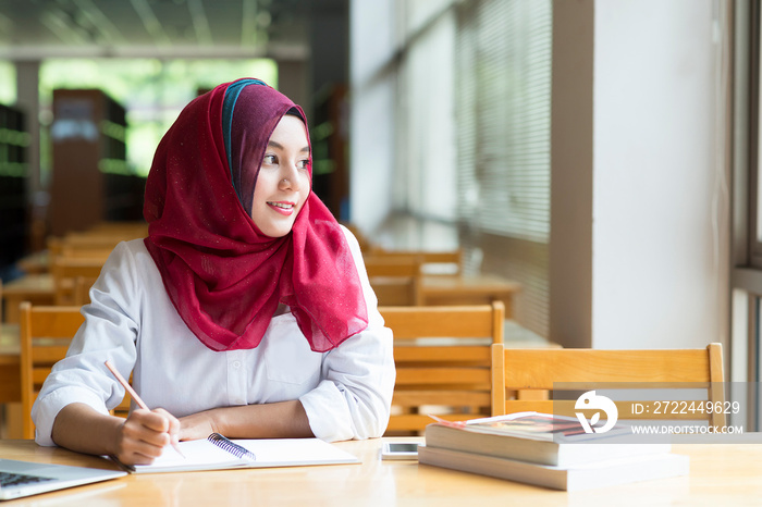 Beautiful young asian muslim woman working with files and laptop.