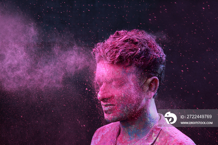 Portrait of a young man plays with Holi colours. Concept for Indian festival Holi