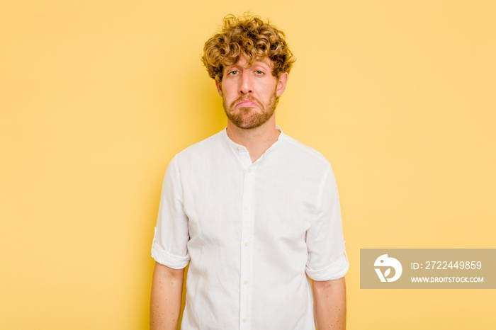 Young caucasian man isolated on yellow background sad, serious face, feeling miserable and displeased.