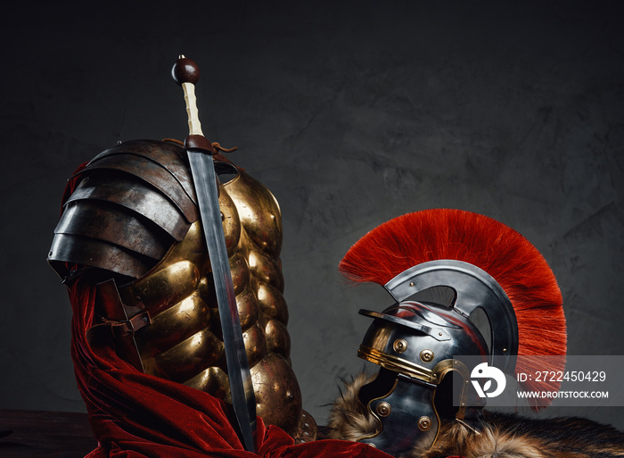 Armored clothing with helmet and sword against dark background