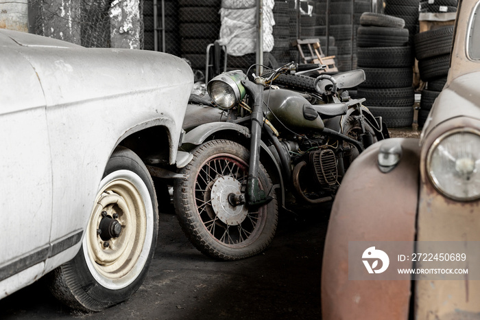 Many rusty abandoned forgotten antique oldtimer old car and motorcycles at junkyard factory storage warehouse indoors. Classic vintage retro vehicles detail garage workshop restore renovation station