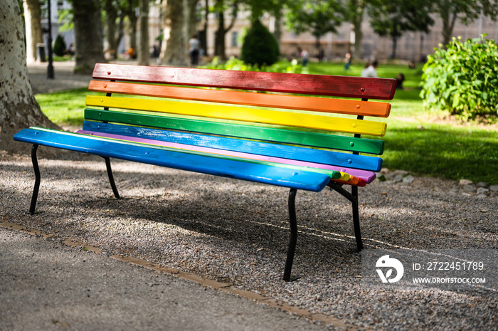 LGBTQ rainbow painted  bench in a park on sunny spring day as a support of gay community in city of Zagreb, Croatia