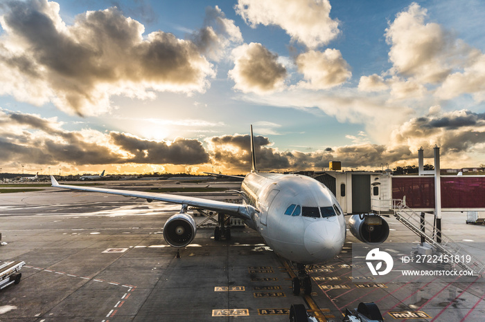 Airplane boarding passengers at airport at sunset