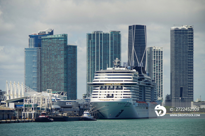 Big modern cruiseship or cruise ship liner MSC Meraviglia in Port of Miami, Florida with downtown skyline and skyscrapers in background waiting for passengers for Caribbean cruising holiday