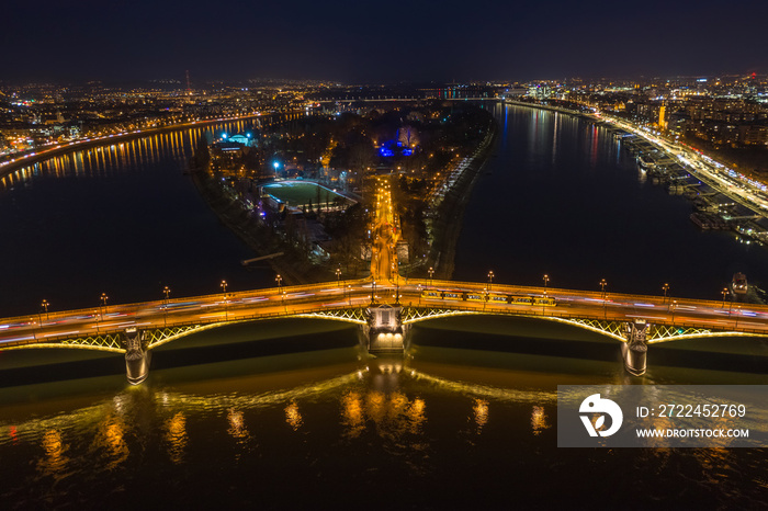 Budapest, Hungary - Aerial view of the illuminated Margaret Bridge with yellow tram on it and Margaret Island at background by night