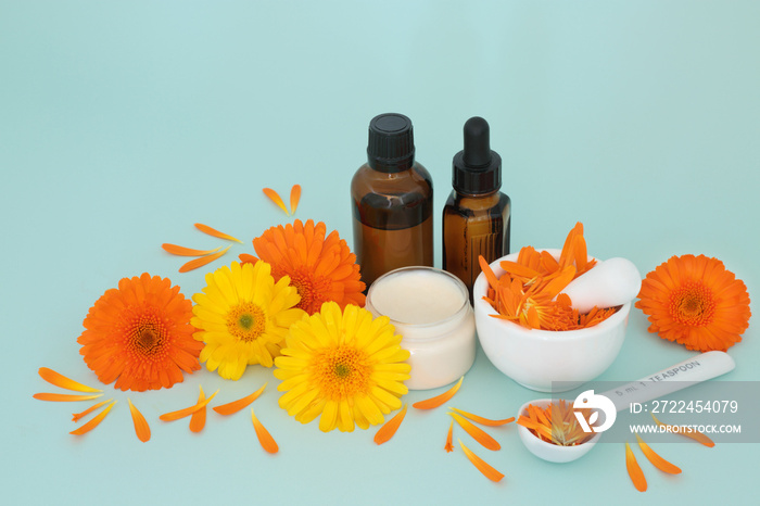 Calendula flowers for skincare with ointment, essential oil bottles and petals in a mortar. Heals wounds, acne, eczema, stimulates collagen, is antiseptic, anti inflammatory, anti bacterial.