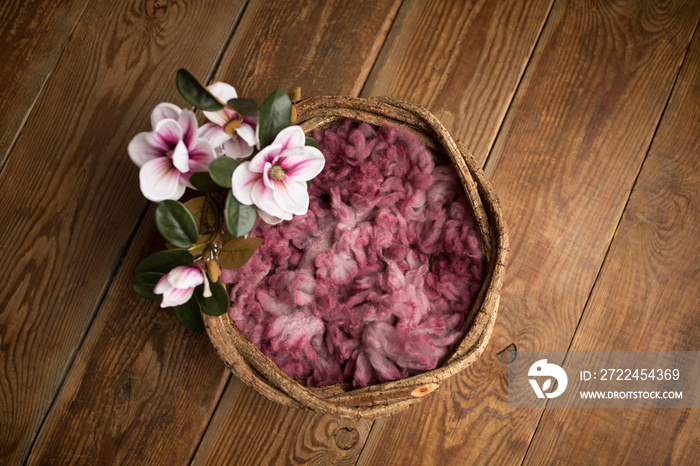 Newborn photography digital background prop. wicker basket with pink fur and flowers on a wooden background.