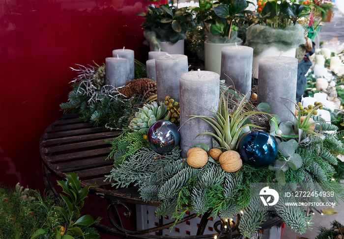 composition with advent wreath and gray candles, nuts, blue glass balls on the table of the flower shop. Christmas preparation concept.