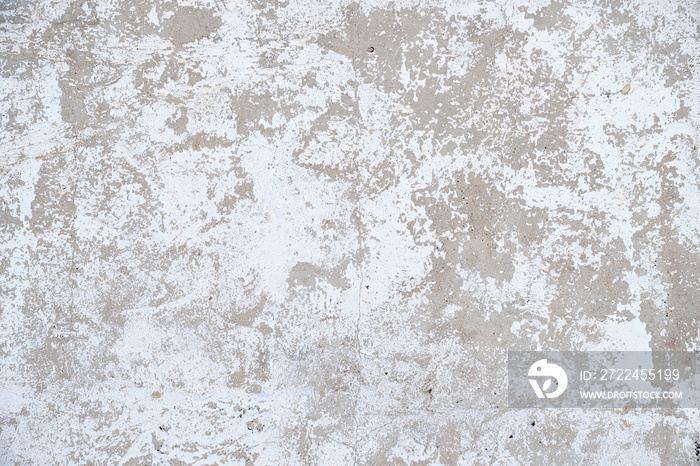 Old, gray concrete wall with peeling white paint.