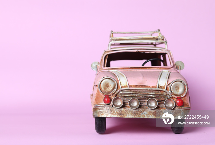 Pink miniature car on pink background, insurance concept