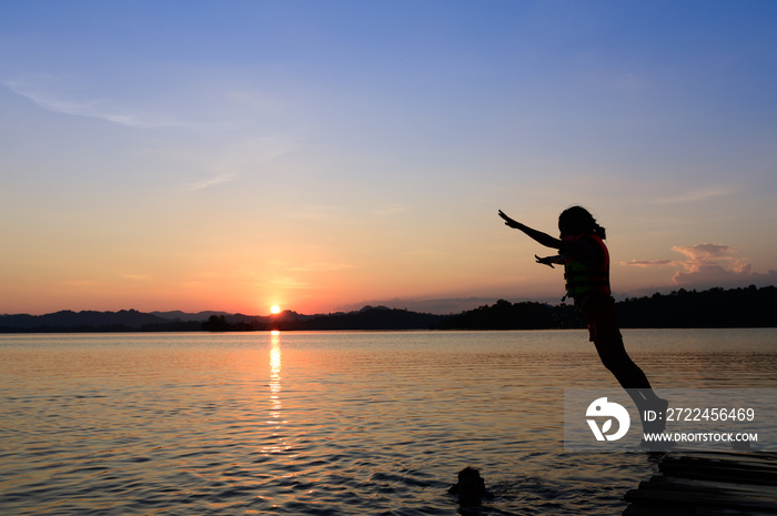 girl jumping in a lake during sunset.